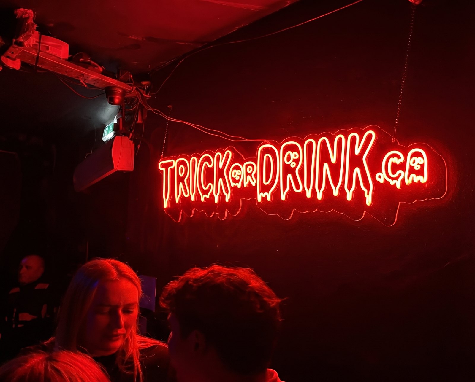 The red Trick or Drink neon sign lit above the crowd at last year's Halloween crawl