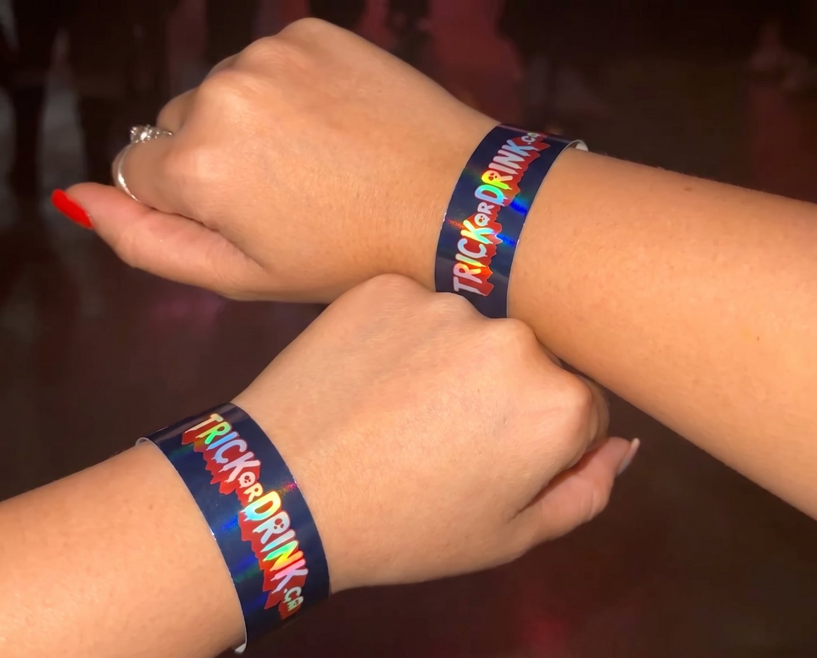 Two Trick or Drink wristbands on crawlers' wrists inside a Toronto club
